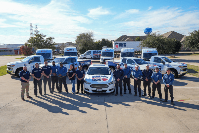 The Jim's Plumbing Now fleet of plumbers standing outside in front of all branded vehicles and trucks.