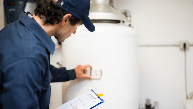 A plumber checking on a white water heater performing a water heater replacement.