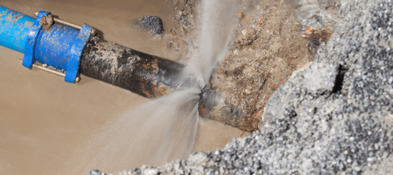 closeup of a water line leak bursting out of a pipe